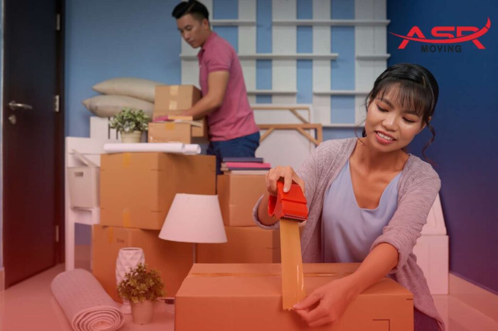 Couple organizing boxes and fragile items such as a lamp