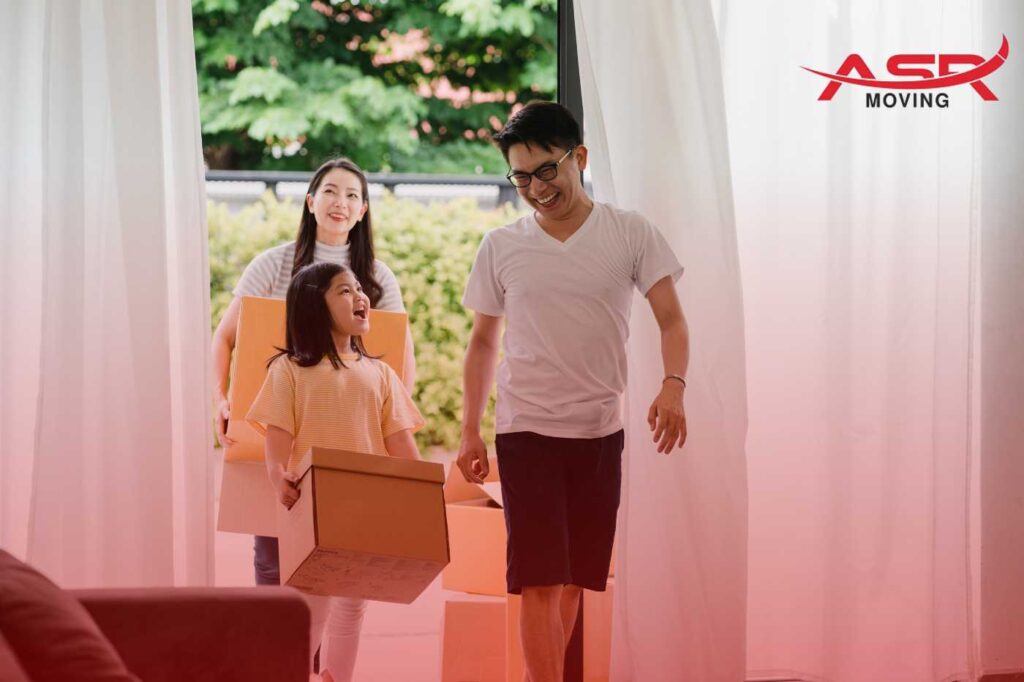 Family carrying packed boxes into their new home during a long-distance relocation.