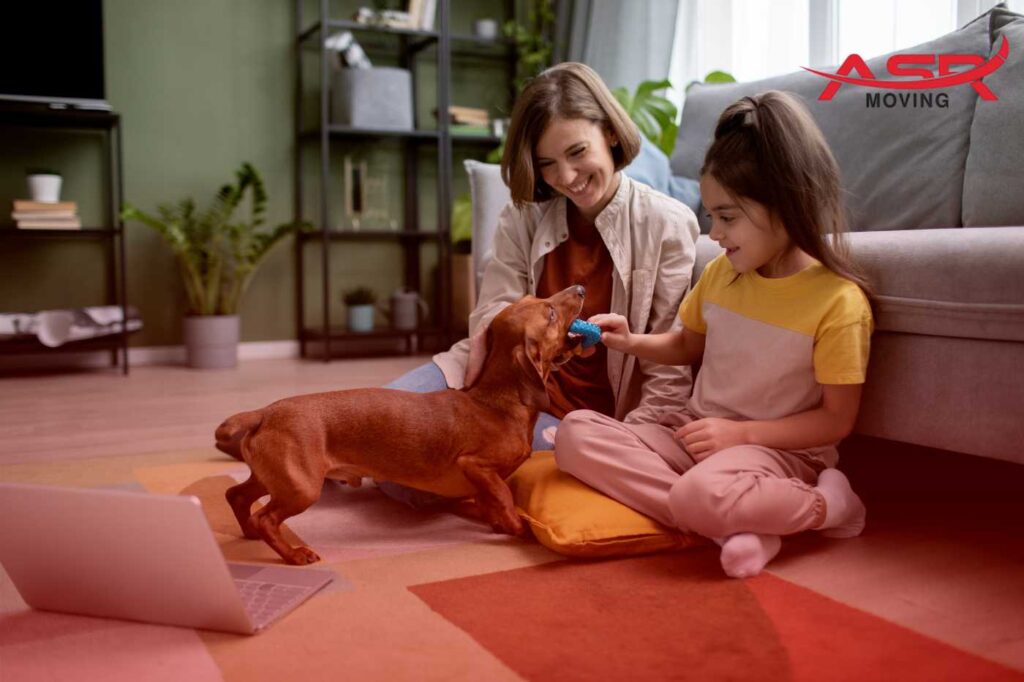 Family sitting on the floor with their dog, reviewing moving plans and packing items for their cross-country move.