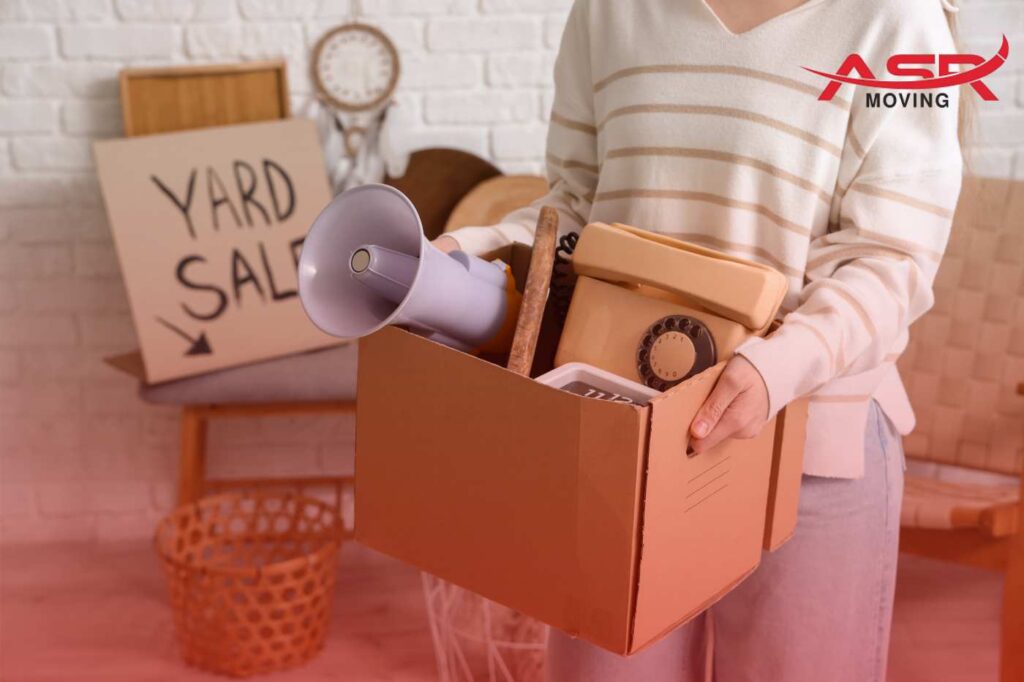 Person holding a moving box during a yard sale to reduce moving costs.