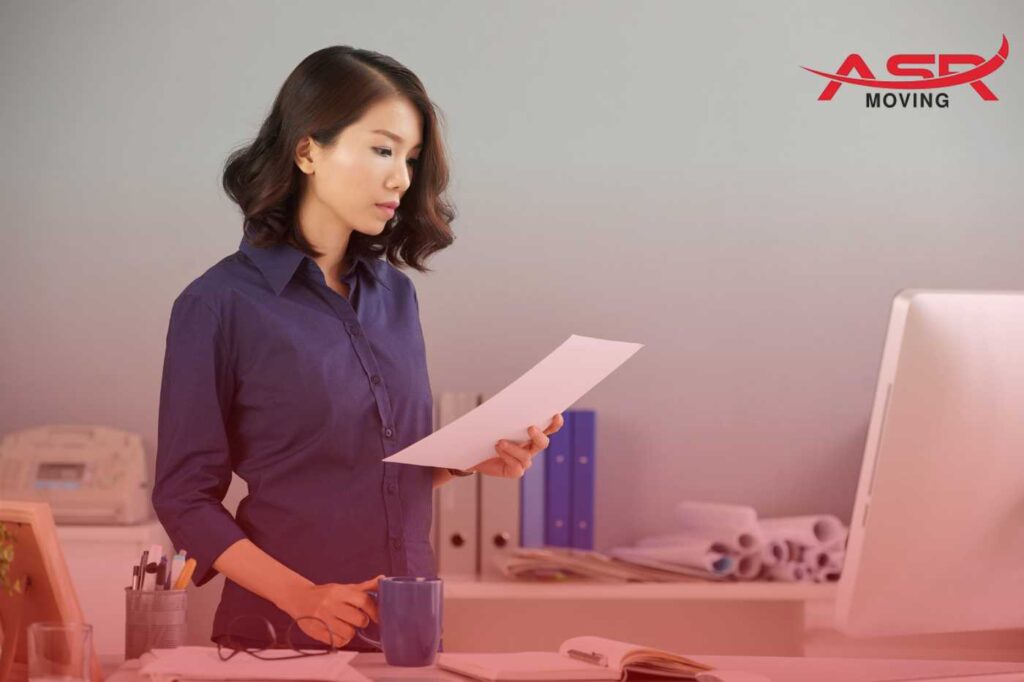 Person reading and checking moving forms, coordinating details for a long-distance relocation.