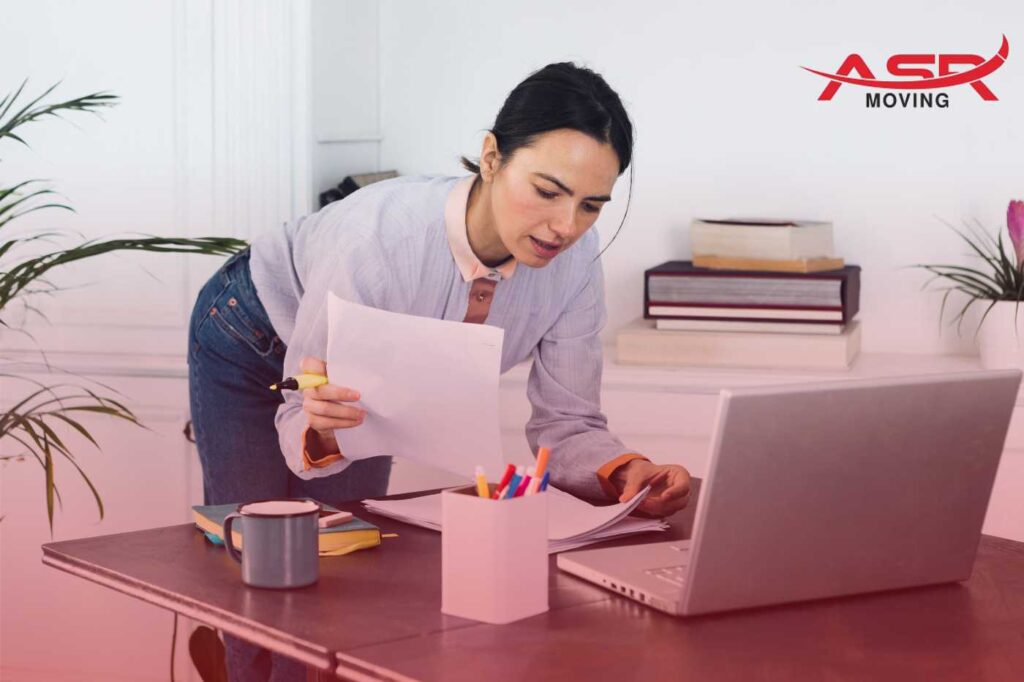 Woman reviewing moving documents at her desk, planning her cross-country move.
