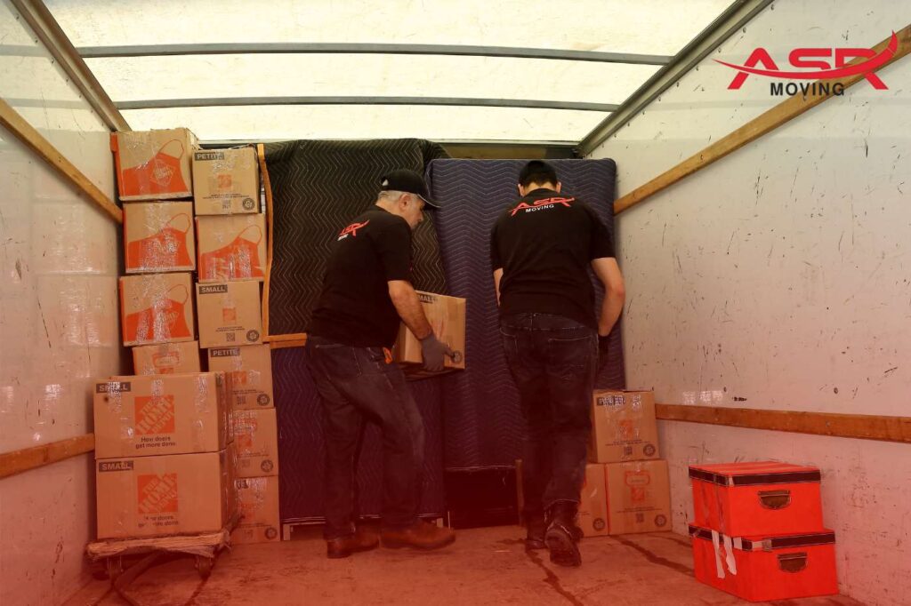 Asr Movers loading stacked boxes and furniture into a moving truck.
