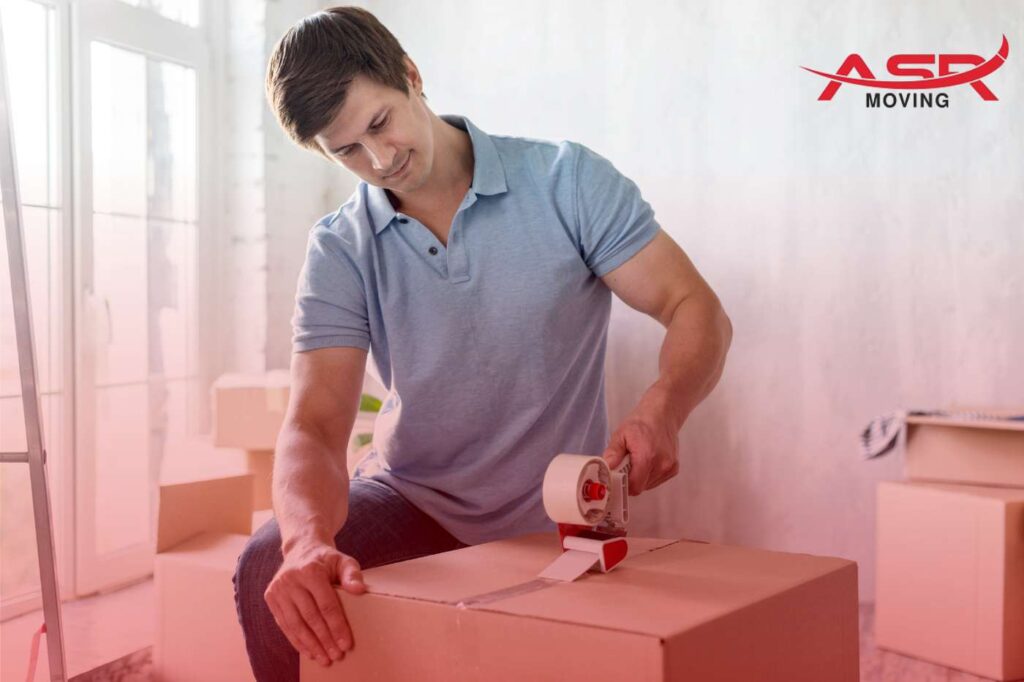 Man sealing a cardboard box with tape as part of packing for a move.
